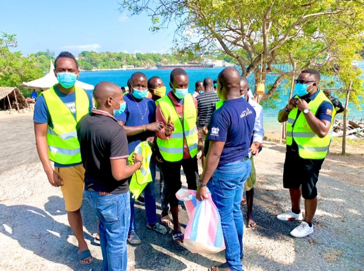 Volunteers in high-visibility vests gathered outdoors by the coast