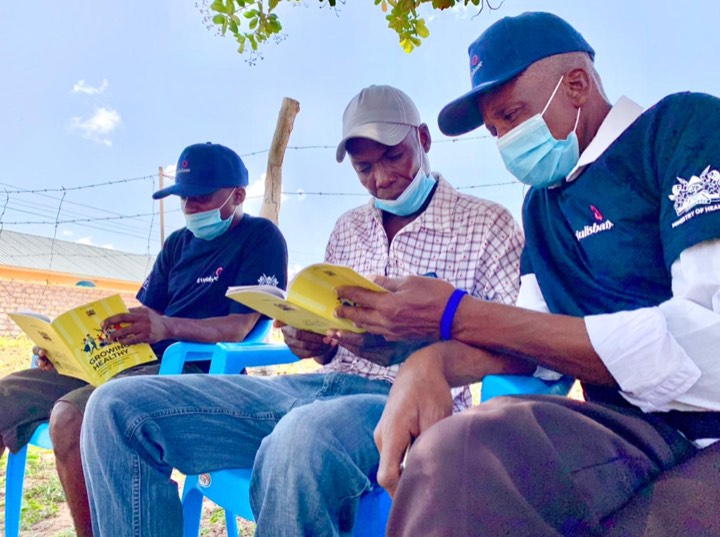 Community members in Tujulishane shirts reading yellow health booklets