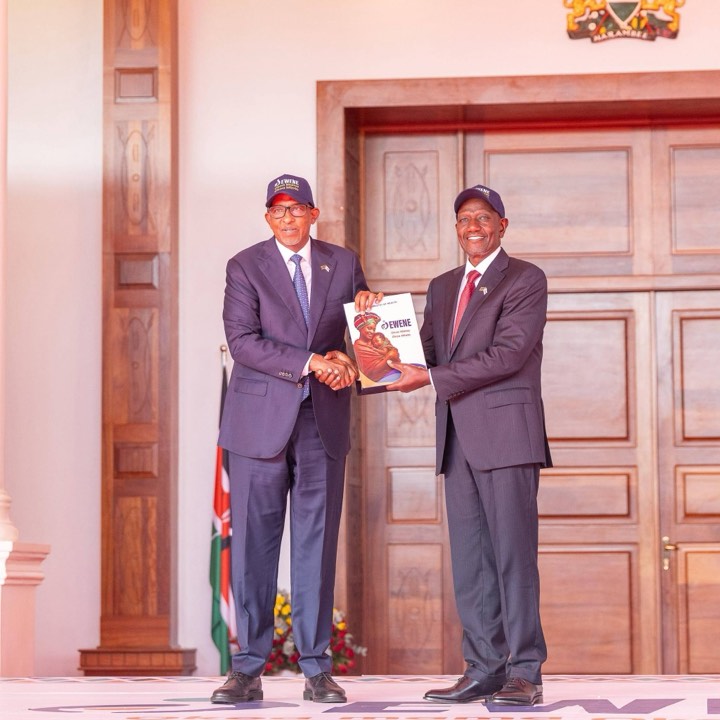 Two leaders shaking hands while holding a copy of the EWENE plan