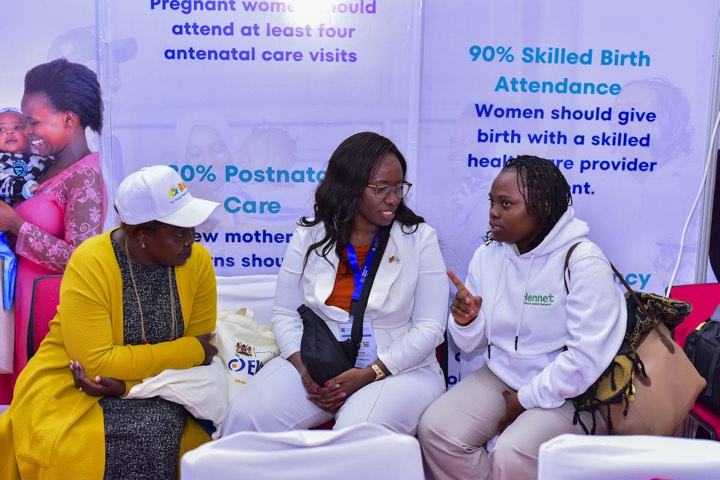 Women seated in front of the EWENE targets display, talking