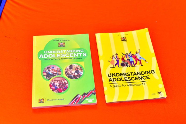 Two guide books on an orange table: Understanding Adolescents for parents, teachers and caregivers, and Understanding Adolescence for adolescents