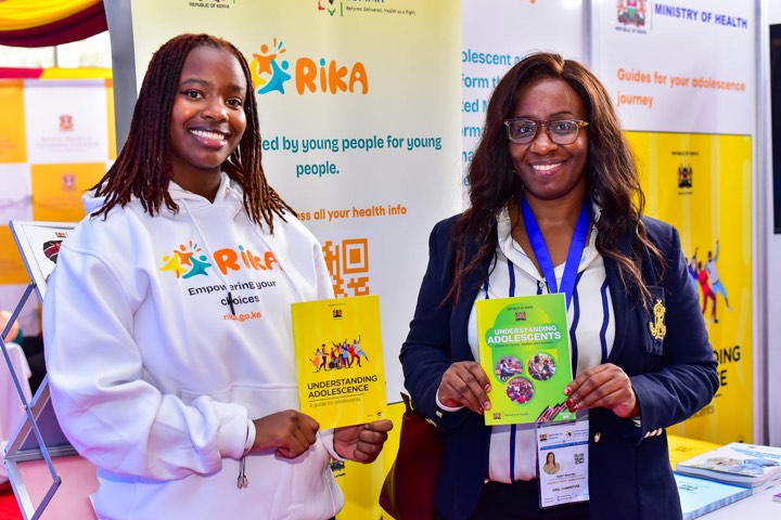 Two smiling women holding Understanding Adolescence guide books