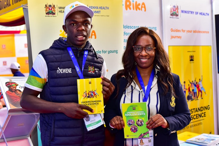 A man in an EWENE jacket and a woman holding Understanding Adolescents guide books
