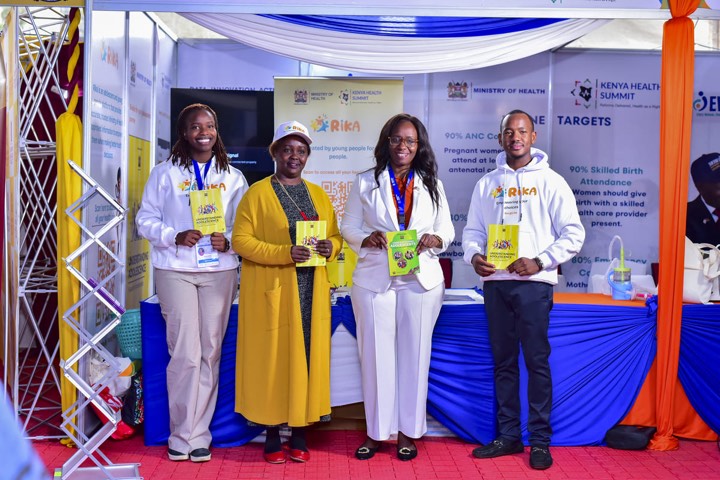 Four people standing at an exhibition stand holding Understanding Adolescence guide books