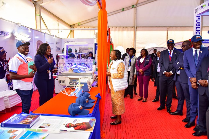 Officials walking past a stand with incubators and EWENE caps on display