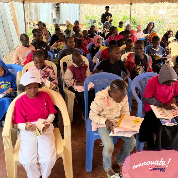 Children under a tent reading guide books during Teenovate