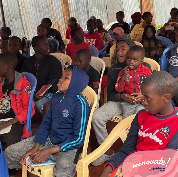 Children seated under a tent listening during a Teenovate session
