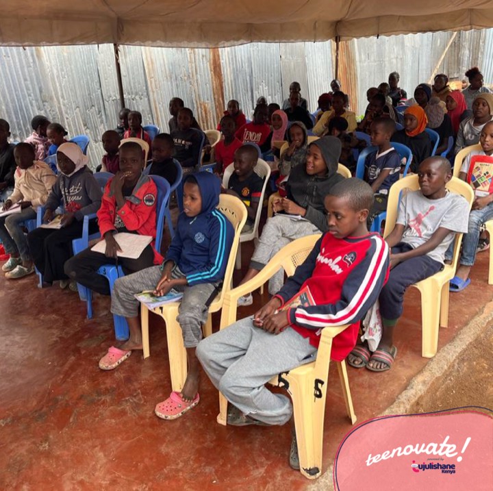 A group of children seated in rows under a tent