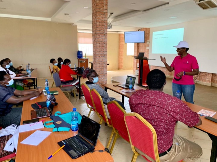 A facilitator presenting to participants with laptops in a training room