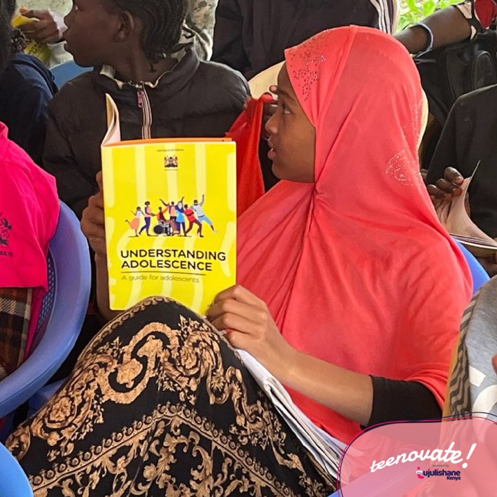 A young woman holding a copy of the Understanding Adolescence guide book