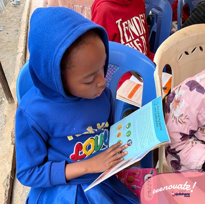 A girl in a blue hoodie reading an illustrated booklet