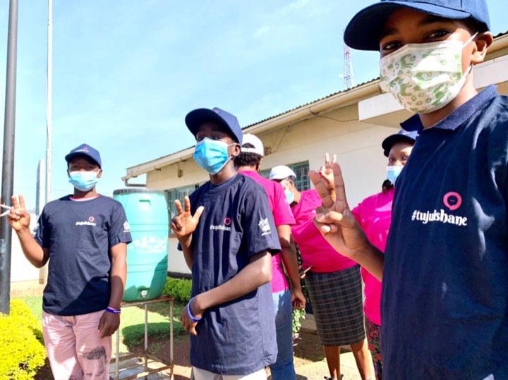 Young people in Tujulishane shirts giving a thumbs up outdoors